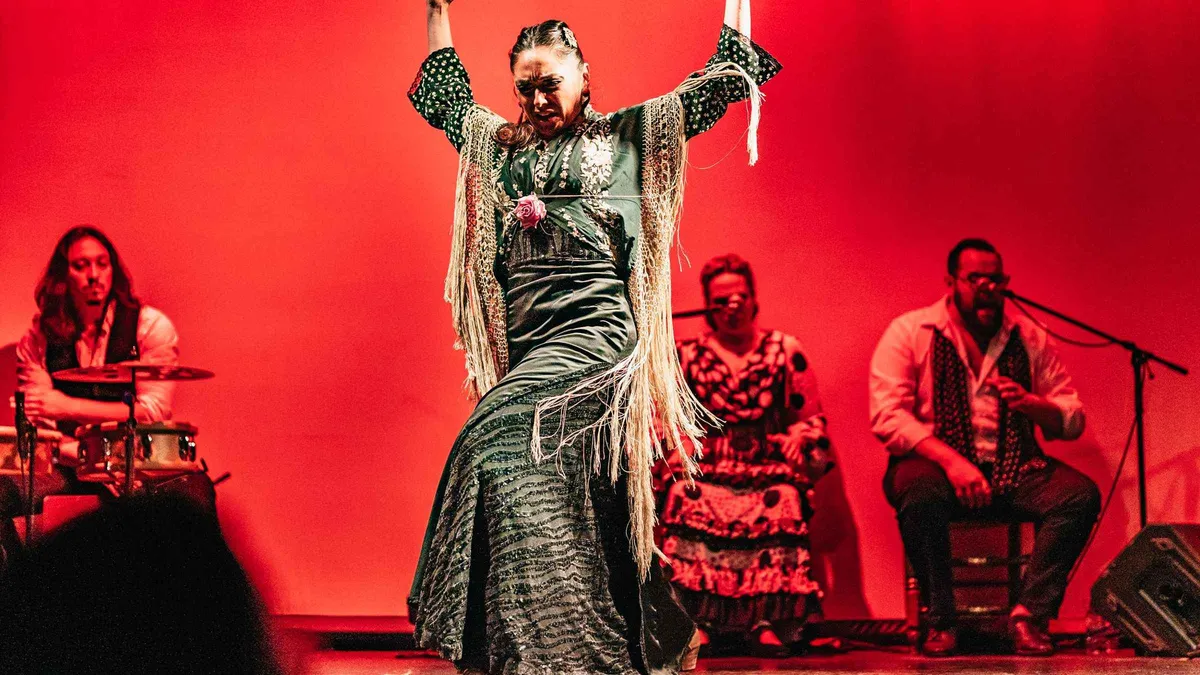 Flamenco dancer mid-turn under stage lights at the City Hall Theatre, a flamenco show in Barcelona, Spain